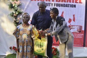 The CEO Jacky Daniel Charity foundation presenting food items to a member of the community.